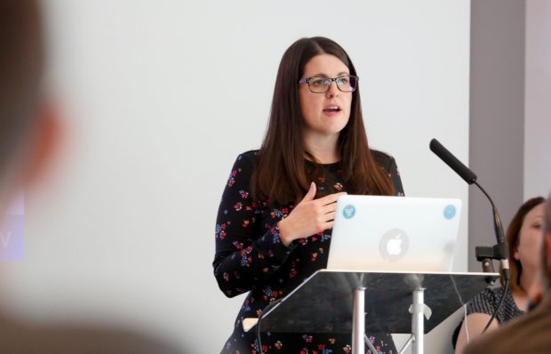 Rachel Woods, product owner, DWP Digital speaking at a conference in front of a laptop