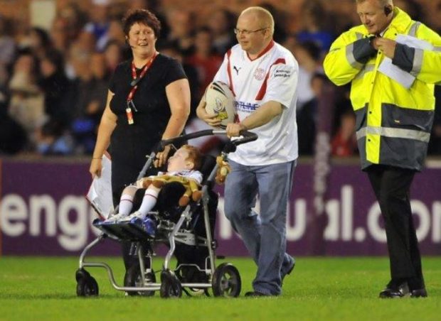 Chris pushes his son Elliott onto the pitch at the St Helen's rugby league the day Elliott got to be the mascot