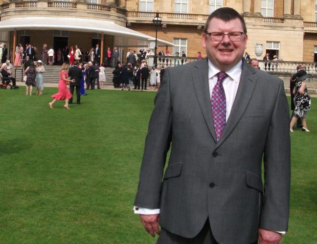 Dennis standing in the grounds of Buckingham Palace