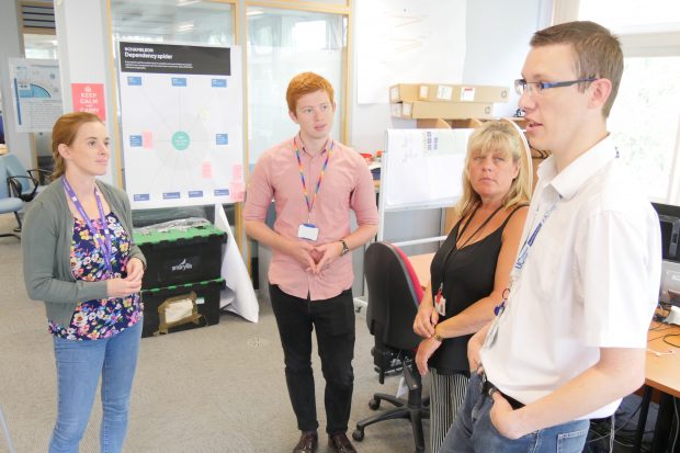 Four DWP Digital colleagues stand in a semi circle during a stand-up in a Digital Hub 