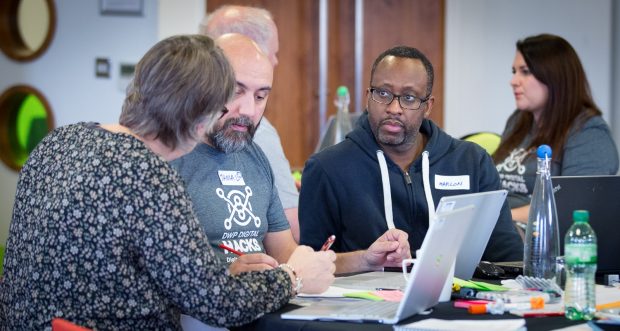 Three people discussing ideas in front of a computer at Hack The North 2.0