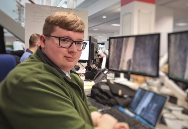 Apprentice Lewis sitting at his desk in front of a computer screen