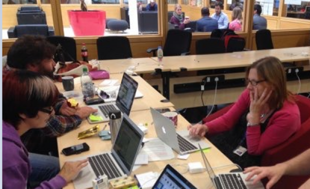 3 members of the Carers Allowance team sit at a desk in front of their computers