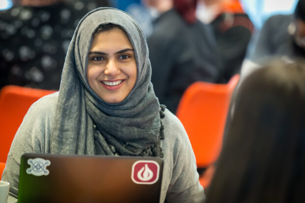 Asma Afzal sitting at a table smiling at another delegate