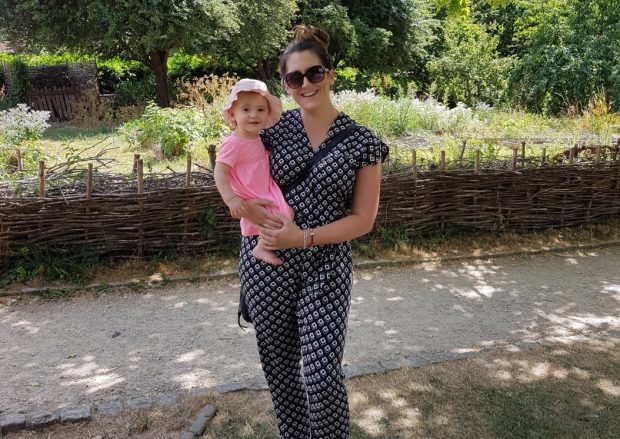 Kirsty stands in garden holding her baby daughter in her arms