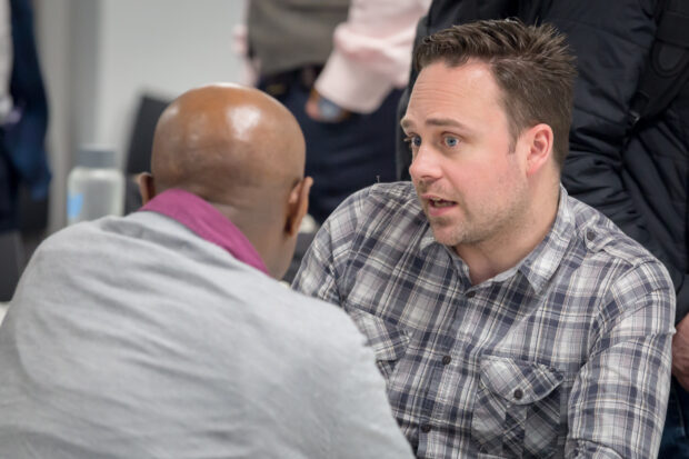 Aaron Jaffery, host of the Women in Digital conference, talks to a male colleague at a table.