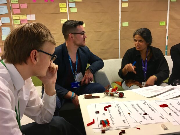 Rashmi and attendees working at a table on the Lego challenge