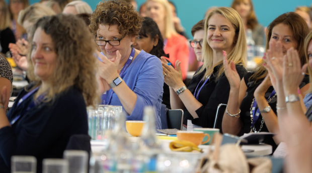 Groups of women sat at tables at the Women in Digital event applaud at the end of a keynote speech