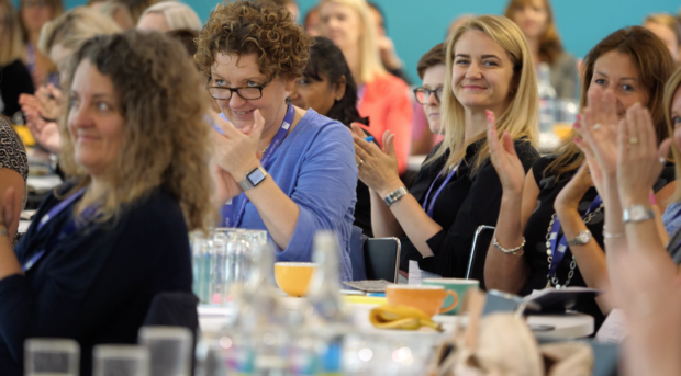 Groups of women sat at tables at the Women in Digital event applaud at the end of a keynote speech