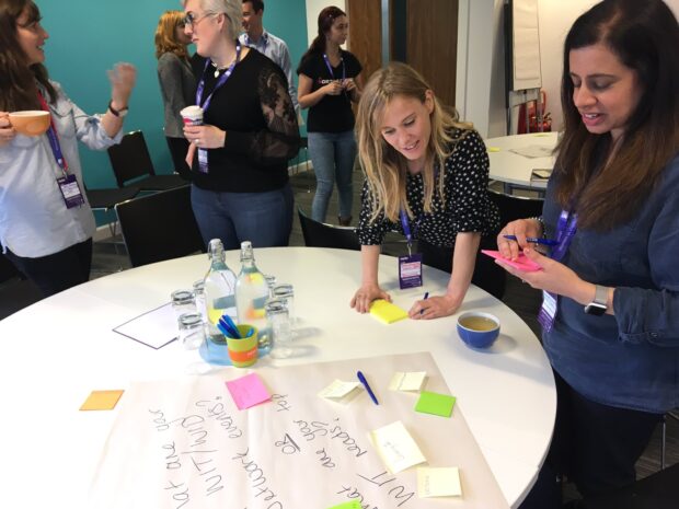 Attendees taking part in a table exercise with pens and post it notes