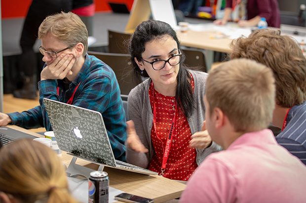 4 people from a hack team at DataJam North East discuss ideas in front of a Mac computer at the event