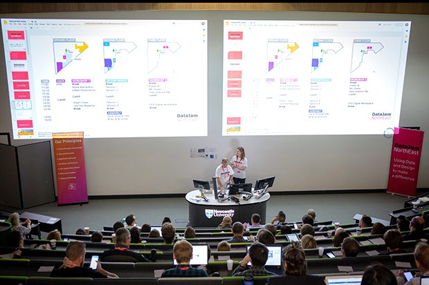 Speakers presenting at the front of the lecture theatre at DataJam NorthEast