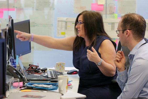 DWP Digital's Head of Integration, Jacqui Legetter at a desk with a colleague looking at a computer screen