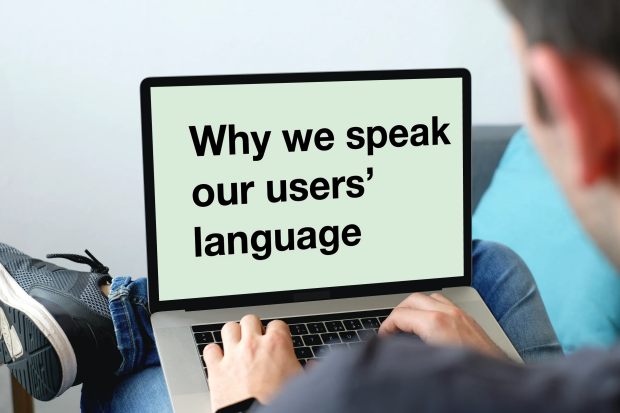 A man sits with a laptop open on his legs. The screen of the laptop shows the blog title 'Why we speak our users' language'