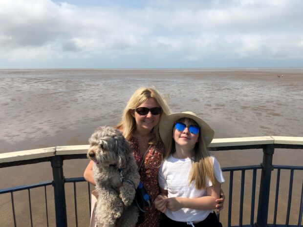 Emma Murray at the side of a beach with her daughter and dog
