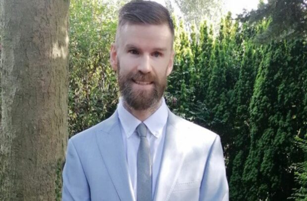 Image shows Andrew outside wearing a suit and tie