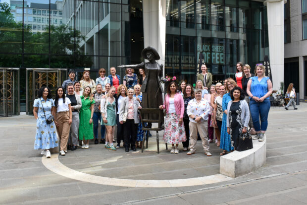 Group of attendees gathered around Emmeline Pankhurst's statue